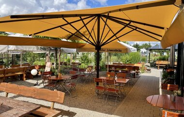 Biergarten mit Biertischen und Schirmen