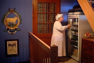 Eine Peson steht in Nachthemd und Mütze vor einem Kühlschrank mit Getränken