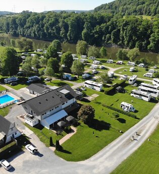 Blick auf einen Campingplatz mit einem Freibad und vielen Wohnmobilen. Im Hintergrund fließt ein Fluß (Neckar). Neckarzimmern im Odenwald