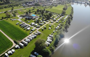 Blick von oben auf einen Campingplatz mit vielen Wohnmobilen. Rechts daneben fließt ein Fluss. Neckarzimmern im Odenwald.