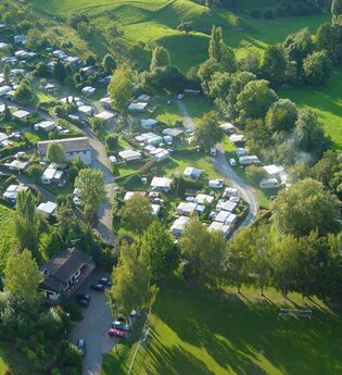 Luftbildaufnahme des Campingplatzes mit Stellplätzen und grünen Wiesen.