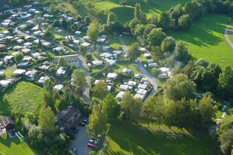Luftbildaufnahme des Campingplatzes mit Stellplätzen und grünen Wiesen.