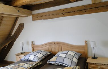 Schlafzimmer in Carles Scheunenhof mit Doppelbett und karierter Bettwäsche