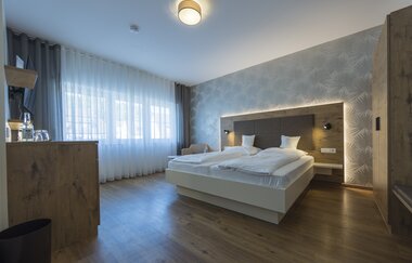 Das Zimmer mit Doppelbett ist in warmen Holztönen eingerichtet