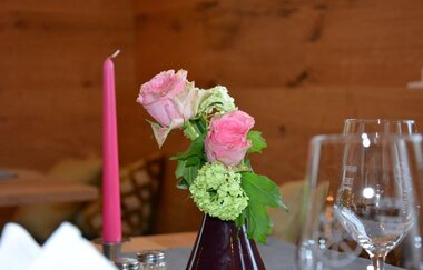 Eine Tischdekoration mit Rosen, Kerze und Gläsern