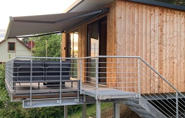 Das Ferienhaus ist aus Holz gebaut und hat außen eine Treppe zum Markise