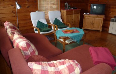 Im Wohnzimmer steht ein Sofa, Sessel und ein TV-Gerät