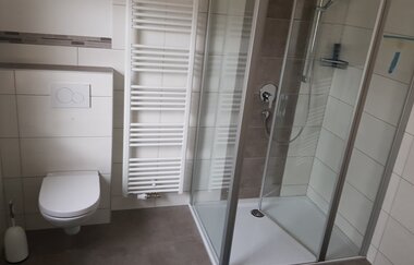 Badezimmer mit bodentiefer Dusche und WC