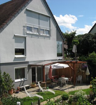 Die Außenansicht des Hauses mit überdachtem Sitzplatz