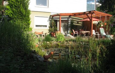 Im Garten erwartet dich ein überdachter Sitzplatz mit Tisch und Stühlen