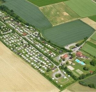Luftaufnahme eines Campingplatzes inmitten von Wiesen und Feldern