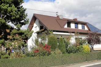 Das Gästehaus ist außen umgeben von vielen grünen Sträuchern.