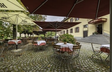 Biergarten mit Biertischen und Sonnenschirmen