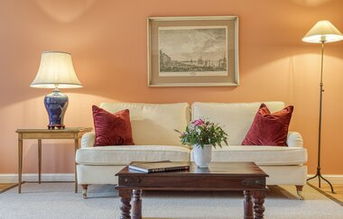 Vor der eleganten Couch in weiß steht ein antiker Tisch