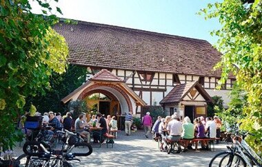 Menschen sitzen im Sommer vor dem Weingut Birkert