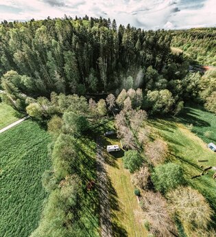 Aufnahme von der Luft aus, ein Wald mit einem Freibad sowie ein Wohnmobilsgtellplatz mit zwei Wohnmobilen. Buchen im Odenwald