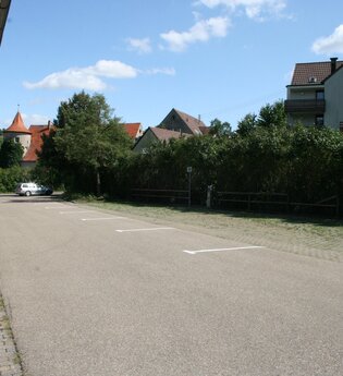 Blick auf den Wohnmobilstellplatz der Stadt Niederstetten. Im Hintergrund ist die Stadt zu sehen. Die Fläche ist asphaltiert.