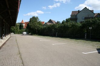 Blick auf den Wohnmobilstellplatz der Stadt Niederstetten. Im Hintergrund ist die Stadt zu sehen. Die Fläche ist asphaltiert.