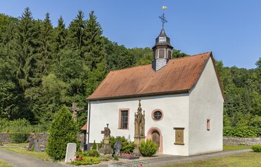 Kleine Kapelle mit einem Turm vor einem Wald. In Billigheim im Odenwald