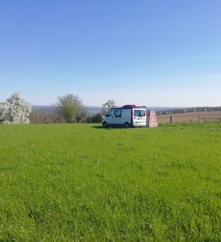 Eine große grüne Wiese mit einem kleineren Wohnmobil. Haßmersheim im Odenwald.