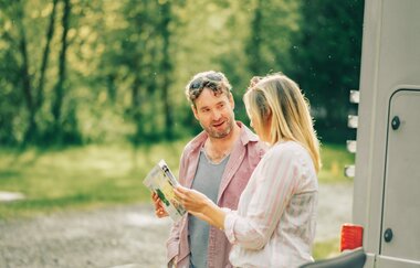 Ein Mann und eine Frau die in eine Karte schauen. Im Hintergrund ist Wald. Odenwald.