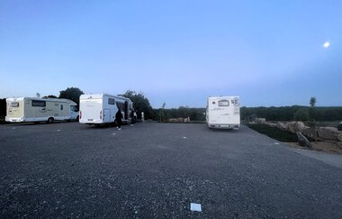Ein geschotterter Platz mit 3 Wohnmobilen in der Dämmerung. Limbach im Odenwald.