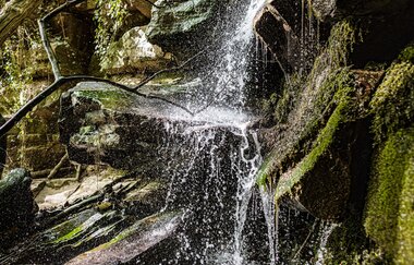 Wasserfall über moosbewachsene Steine. Odenwald.