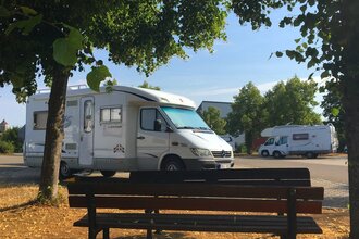 Blick auf eine Bank am Wohnmobilstellplatz P2 in Rothenburg o.d.T., umrahmt von Bäumen.