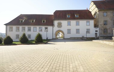 Es sind zwei Gebäudeteile eines Schlosses zu sehen. Davor ein gepflasterter Platz. Ravenstein im Odenwald.