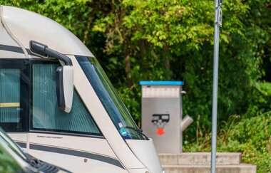Wohnmobilstellplatz mit Wohnmobilen und Entsorgungsstation im Hintergrund.
