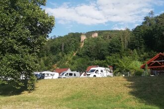 Blick auf den Wohnmobilstellplatz am Stadteingang Süd in Freudenberg am Main. Im Hintergrund ist von Wald umgeben die Freudenburg zu sehen.