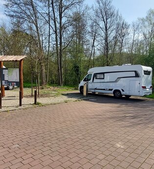 Ein gepflasterter Platz mit zwei weißen Wohnmobilen. Im Hintergrund ist eine Informationstafel. Mosbach im Odenwald.