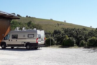 Wohnmobil auf einem Schotterplatz bei gutem Wetter mit Weinbergen im Hintergrund