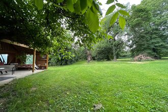 Blick auf den Wohnmobilstellplatz auf dem Ferienbauernhof Schamman in Neubronn. Es ist eine von Bäumen umgebene Wiese mit einer Pergola zu sehen.