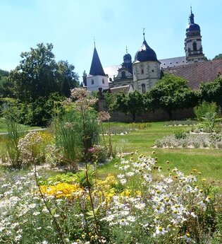 Im Garten blühen Arzneipflanzen und man kann auf das Kloster schauen
