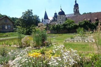 Im Garten blühen Arzneipflanzen und man kann auf das Kloster schauen