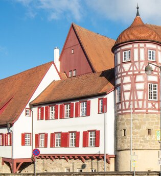 altes Schloss - rechts das Torhaus mit Sockelgeschoss aus hellem Sandstein und aufgesetztem roten Fachwerk mit weißen Gefachen, flankiert von zwei Rundtürmen. In der Bildmitte der Westflügel mit zwei aneinandergebauten, weiß verputzten Gebäudeteilen mit r