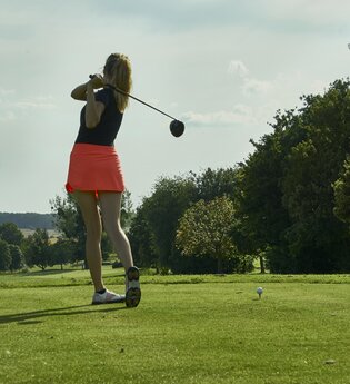 Eine Frau beim Golfabschlag auf dem Platz