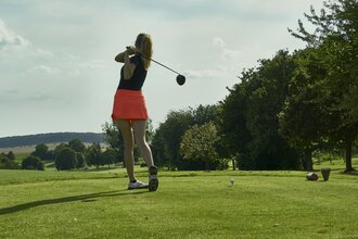 Eine Frau beim Golfabschlag auf dem Platz
