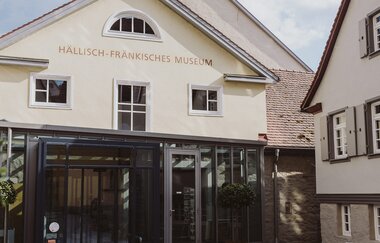 Eingang des Hällisch-Fränkischen Museums in Schwäbisch Hall mit Glasfassade und historischen Gebäuden.