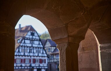 Fachwerkgebäude im Klosterhof Maulbronn durch einen steinernen Fensterbogen betrachtet