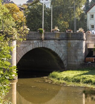 Das Bild zeigt eine Steinbrücke über einem Fluss