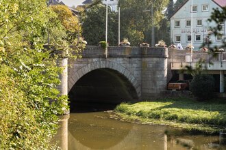 Das Bild zeigt eine Steinbrücke über einem Fluss