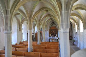 Blick in den Innenbereich der Klosterkirche Frauental. Es sind die Deckengewölbe und die Sitzreihen sowie der Altar zu sehen.