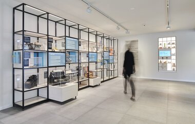 Eine Person bewegt sich auf Vitrinen mit Ausstellungsgegenständen zu