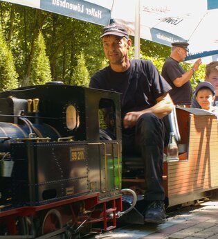 Dampfeisenbahnführer mit Fahrgästen auf Miniatureisenbahn