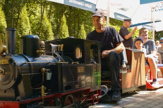 Dampfeisenbahnführer mit Fahrgästen auf Miniatureisenbahn