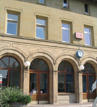 Das Bahnhofsgebäude von außen, hier hängt ein DB-Schild und eine Uhr