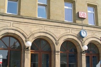 Das Bahnhofsgebäude von außen, hier hängt ein DB-Schild und eine Uhr