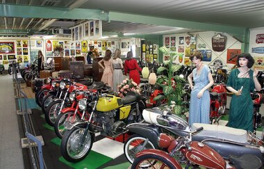Im Museum stehen alte Motorräder und Schaufensterpuppen mit Kleidung aus vergangenen Zeiten